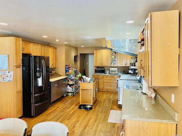 kitchen with a center island, black refrigerator with ice dispenser, sink, light hardwood / wood-style floors, and light stone counters