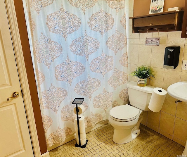 bathroom featuring tile patterned floors, toilet, and tile walls