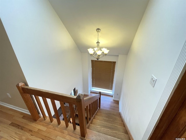 stairs featuring a chandelier and wood-type flooring