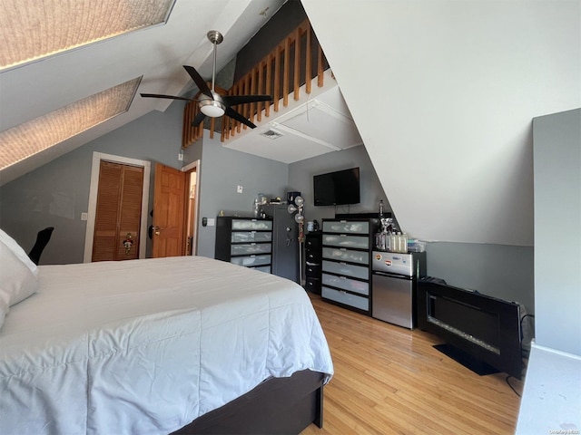 bedroom with a closet, light hardwood / wood-style flooring, ceiling fan, and lofted ceiling