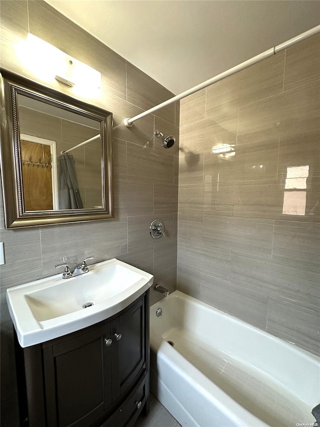 full bath featuring shower / tub combo, tile walls, backsplash, and vanity