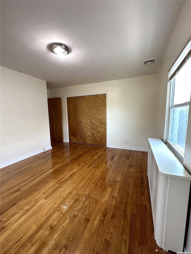 spare room featuring visible vents, baseboards, and wood finished floors