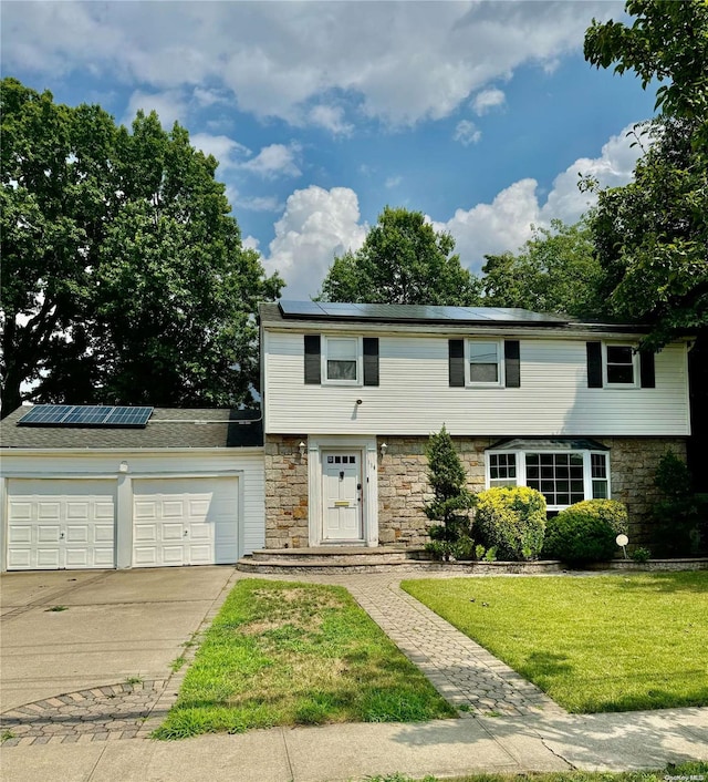 view of front of home featuring a front yard, solar panels, and a garage