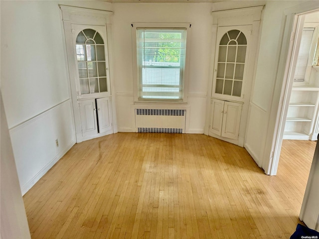 unfurnished dining area featuring radiator heating unit and light wood-type flooring