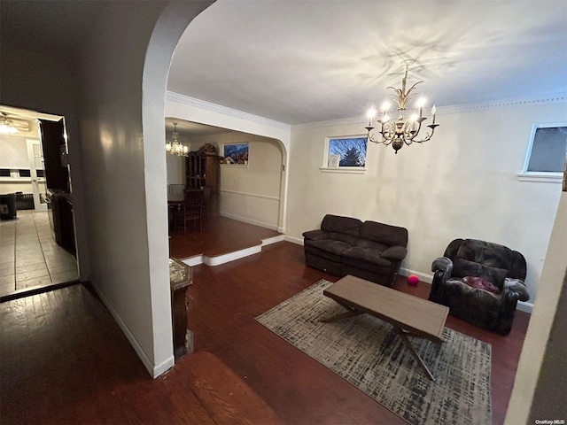 living room featuring hardwood / wood-style floors, ceiling fan with notable chandelier, and ornamental molding