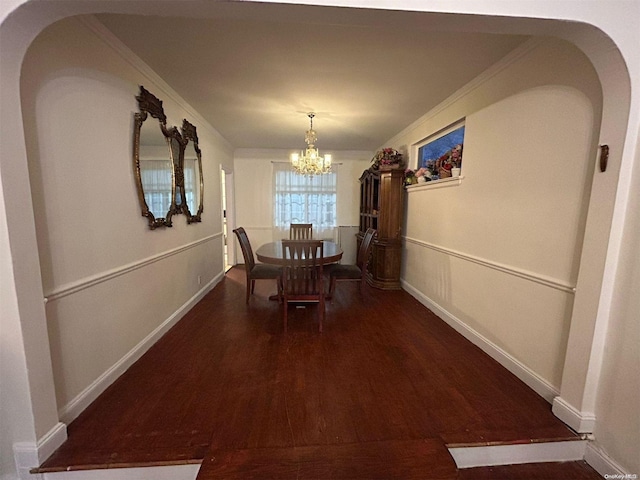 unfurnished dining area featuring dark hardwood / wood-style flooring, crown molding, and an inviting chandelier