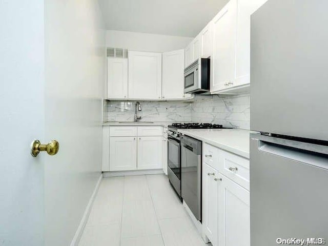 kitchen with white cabinetry, sink, appliances with stainless steel finishes, and tasteful backsplash