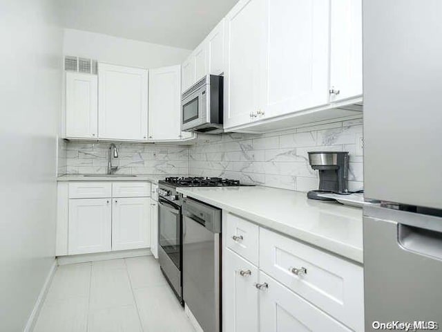 kitchen with backsplash, white cabinetry, sink, and appliances with stainless steel finishes