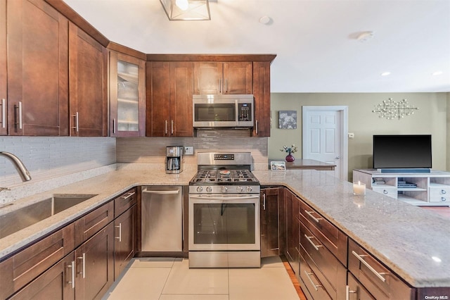 kitchen featuring light tile patterned floors, appliances with stainless steel finishes, sink, and light stone countertops