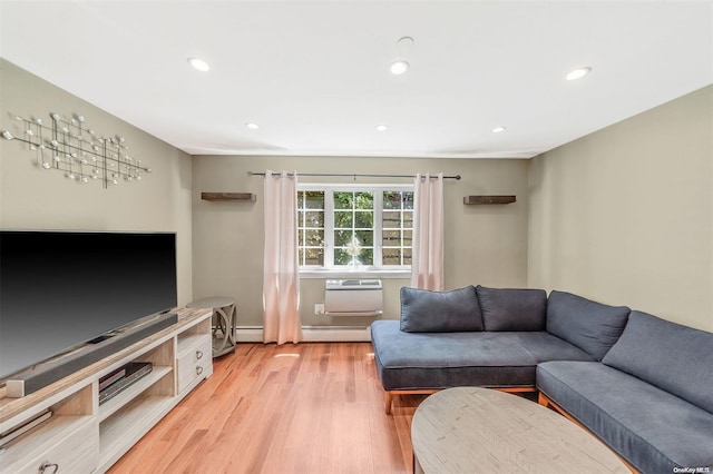 living room with a baseboard heating unit, a wall unit AC, and light hardwood / wood-style floors