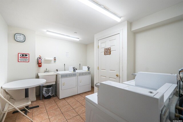 laundry area featuring separate washer and dryer, light tile patterned floors, and sink