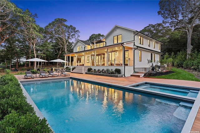 back house at dusk with a patio area and a pool with hot tub