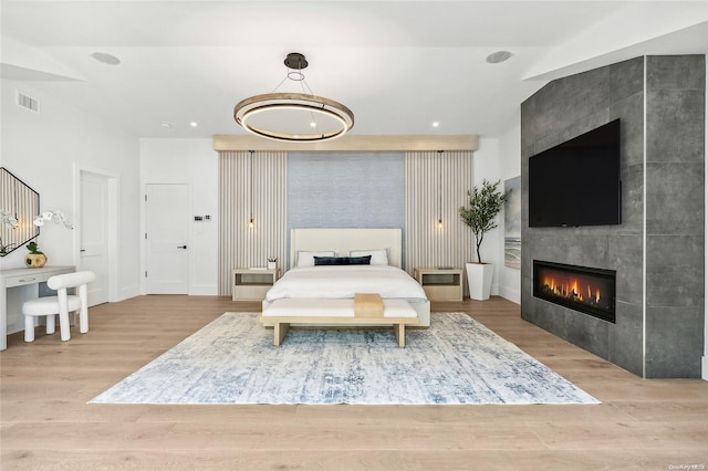 bedroom featuring a tile fireplace and light wood-type flooring