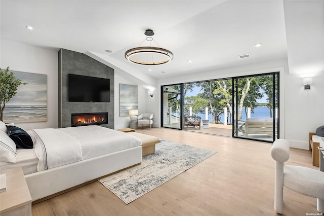 bedroom with access to outside, a large fireplace, wood-type flooring, and lofted ceiling