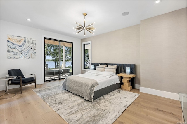 bedroom featuring access to outside, a chandelier, and light wood-type flooring