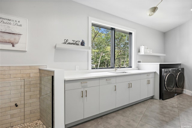 laundry room featuring washing machine and dryer, sink, light tile patterned floors, and cabinets