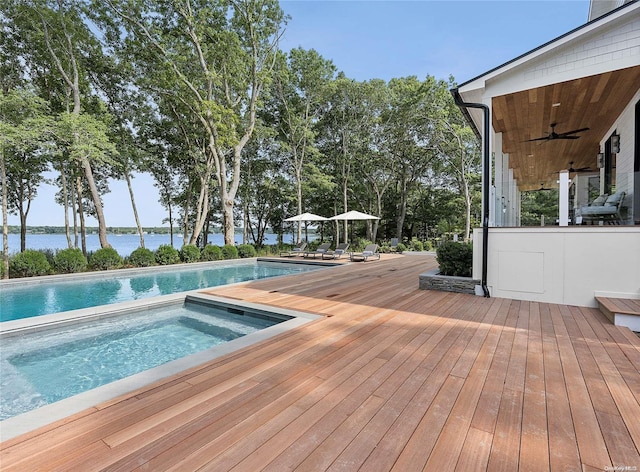 view of pool with ceiling fan, a deck with water view, and an in ground hot tub