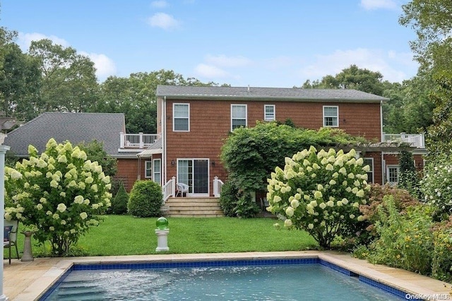 back of house with a lawn and a balcony