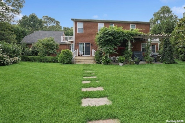 back of house featuring a lawn and a balcony