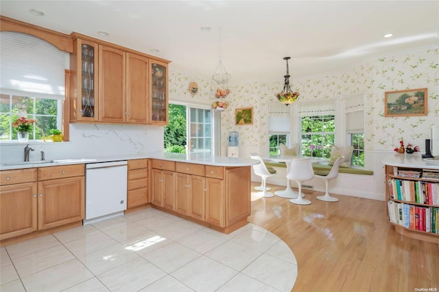 kitchen featuring dishwasher, sink, light hardwood / wood-style flooring, decorative light fixtures, and kitchen peninsula