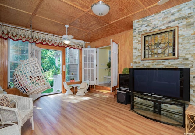 living room featuring hardwood / wood-style flooring, ceiling fan, wood walls, and wooden ceiling