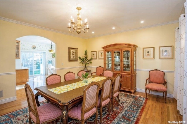 dining space featuring crown molding, an inviting chandelier, and light wood-type flooring