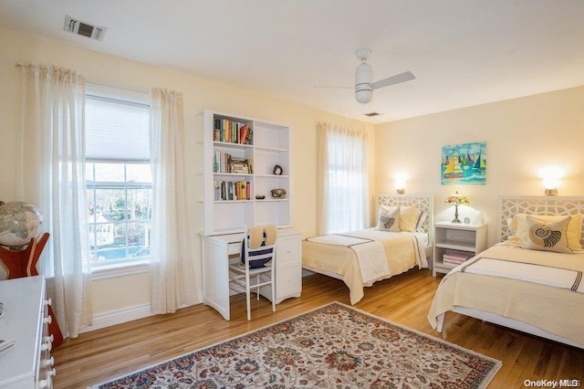 bedroom with multiple windows, ceiling fan, and hardwood / wood-style floors