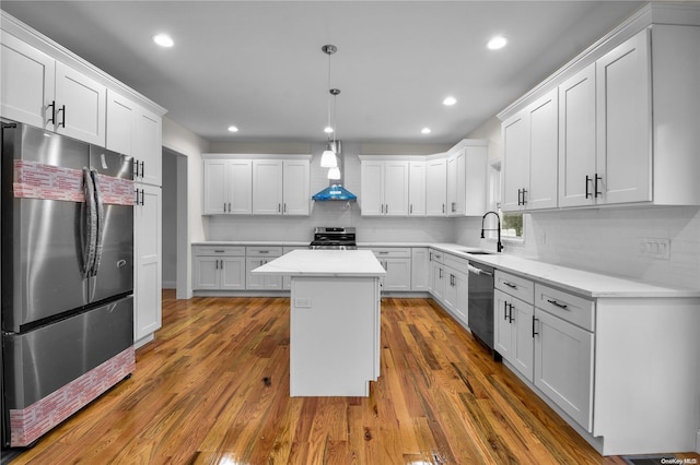 kitchen featuring wall chimney exhaust hood, a kitchen island, dark hardwood / wood-style flooring, and appliances with stainless steel finishes