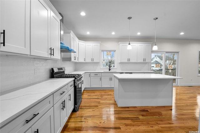 kitchen with pendant lighting, light hardwood / wood-style floors, white cabinetry, and stainless steel range with gas stovetop