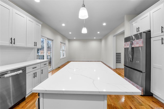 kitchen featuring white cabinets, appliances with stainless steel finishes, decorative light fixtures, and a kitchen island