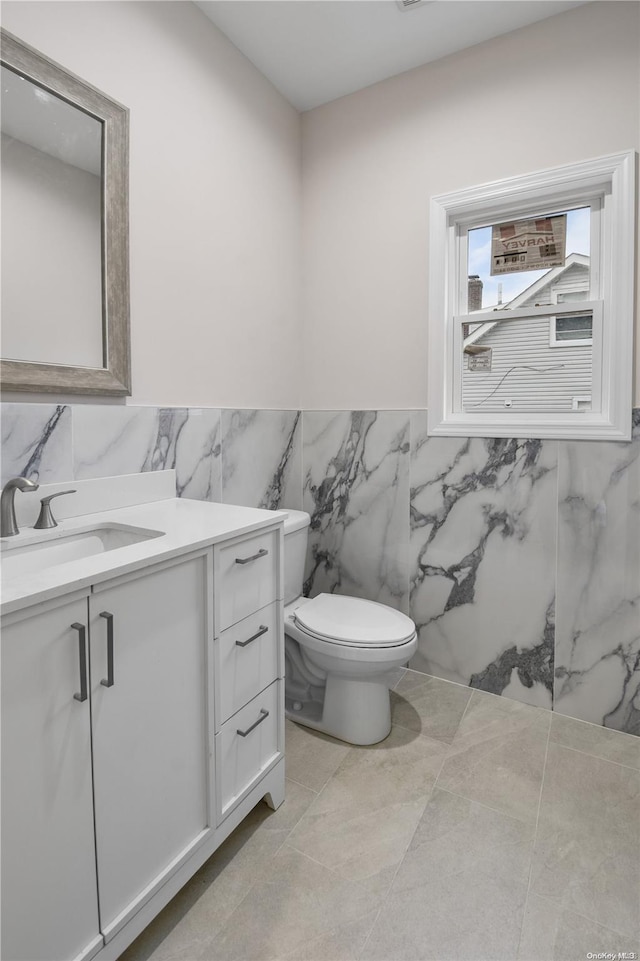 bathroom featuring tile patterned flooring, vanity, tile walls, and toilet