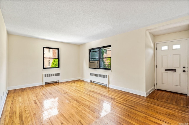 entrance foyer with a textured ceiling, radiator, and light hardwood / wood-style flooring