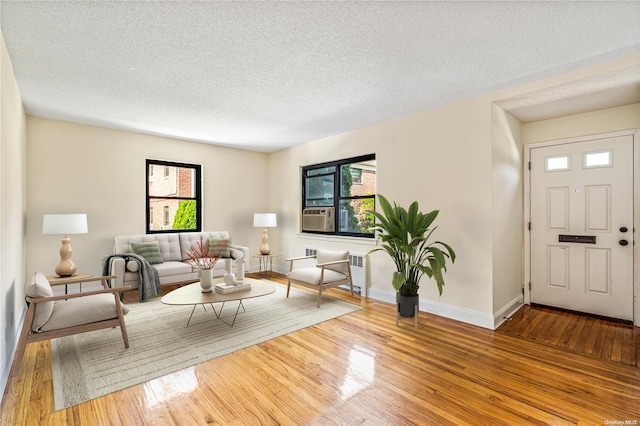 living room featuring radiator heating unit, a textured ceiling, and light hardwood / wood-style floors