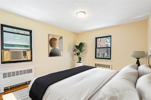 bedroom featuring multiple windows, wood-type flooring, and radiator