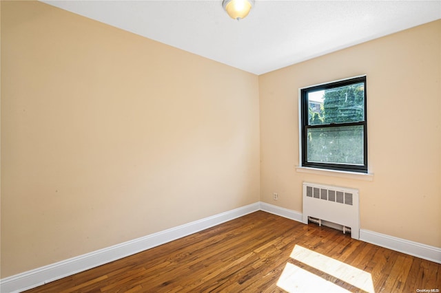 unfurnished room featuring hardwood / wood-style floors and radiator heating unit