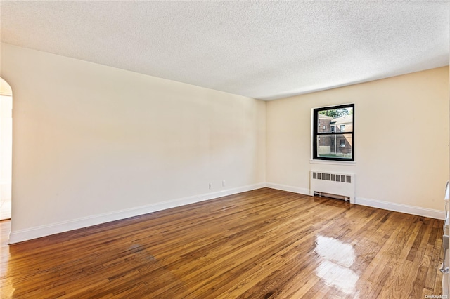 spare room featuring radiator, a textured ceiling, and hardwood / wood-style flooring