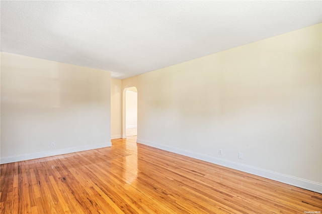 unfurnished room featuring light wood-type flooring and a textured ceiling