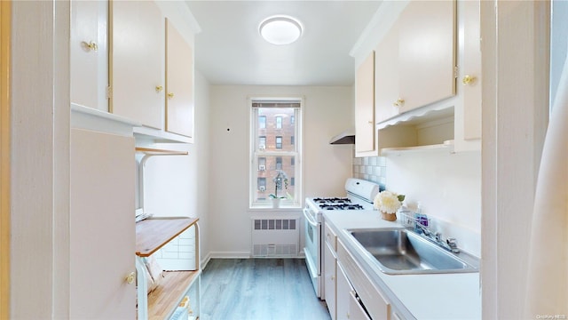 kitchen featuring white stove, white cabinetry, and sink