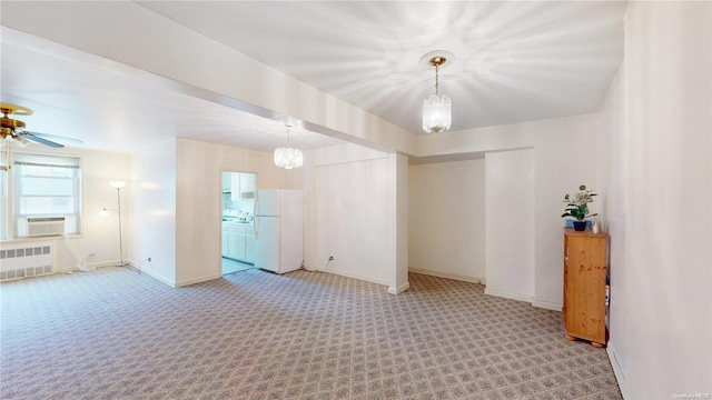 carpeted spare room featuring radiator, cooling unit, and ceiling fan with notable chandelier