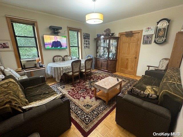 living room with cooling unit, crown molding, and light parquet flooring