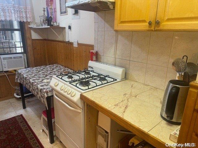 kitchen featuring tile countertops, cooling unit, white gas stove, and range hood