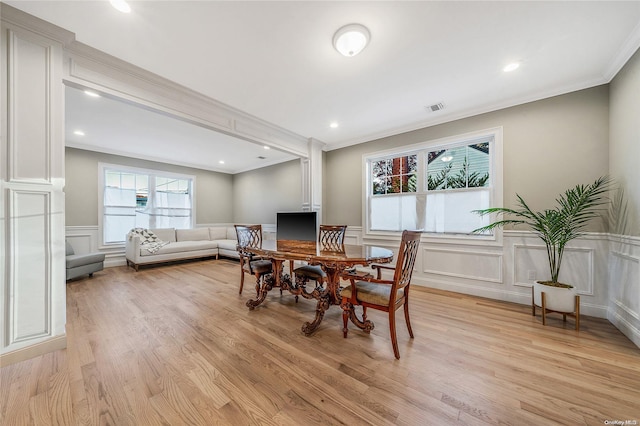 dining space with light hardwood / wood-style floors and ornamental molding