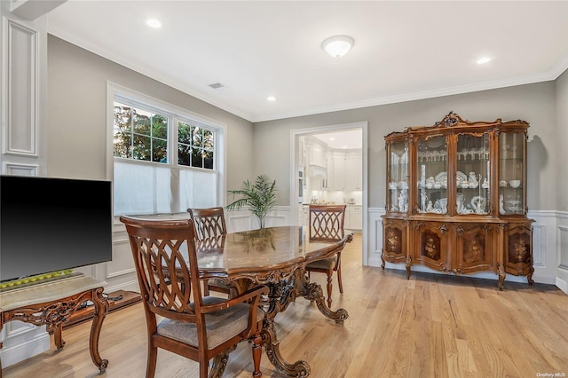 dining room featuring ornamental molding and light wood-type flooring