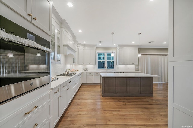 kitchen featuring decorative light fixtures, light wood-type flooring, white cabinetry, and stainless steel appliances