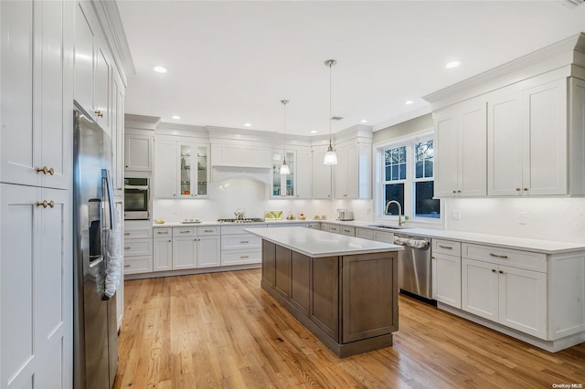 kitchen with white cabinetry, light hardwood / wood-style floors, pendant lighting, a kitchen island, and appliances with stainless steel finishes