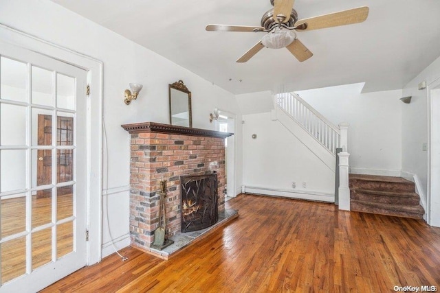 unfurnished living room featuring ceiling fan, a fireplace, a baseboard radiator, and wood-type flooring