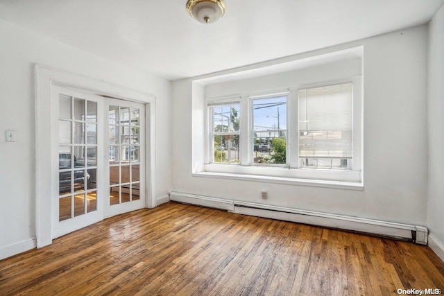 unfurnished room featuring baseboard heating and dark wood-type flooring