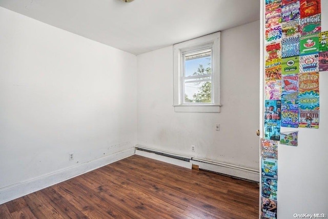 empty room featuring a baseboard heating unit and dark wood-type flooring