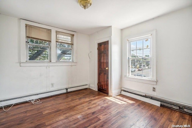 spare room featuring dark wood-type flooring and a baseboard heating unit