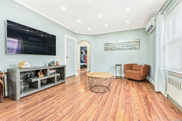 living area featuring an AC wall unit, crown molding, a wealth of natural light, light hardwood / wood-style floors, and radiator heating unit